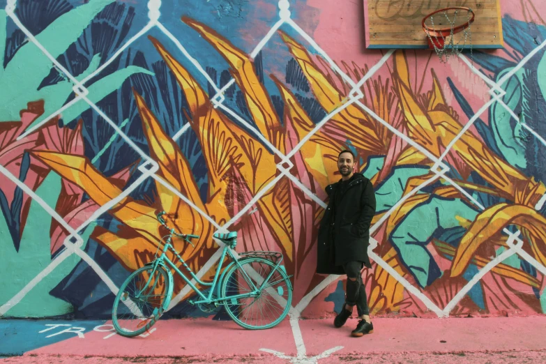 woman with bicycle by brightly painted wall outdoors