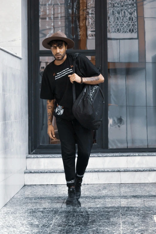 a man carrying a bag down a sidewalk in the rain