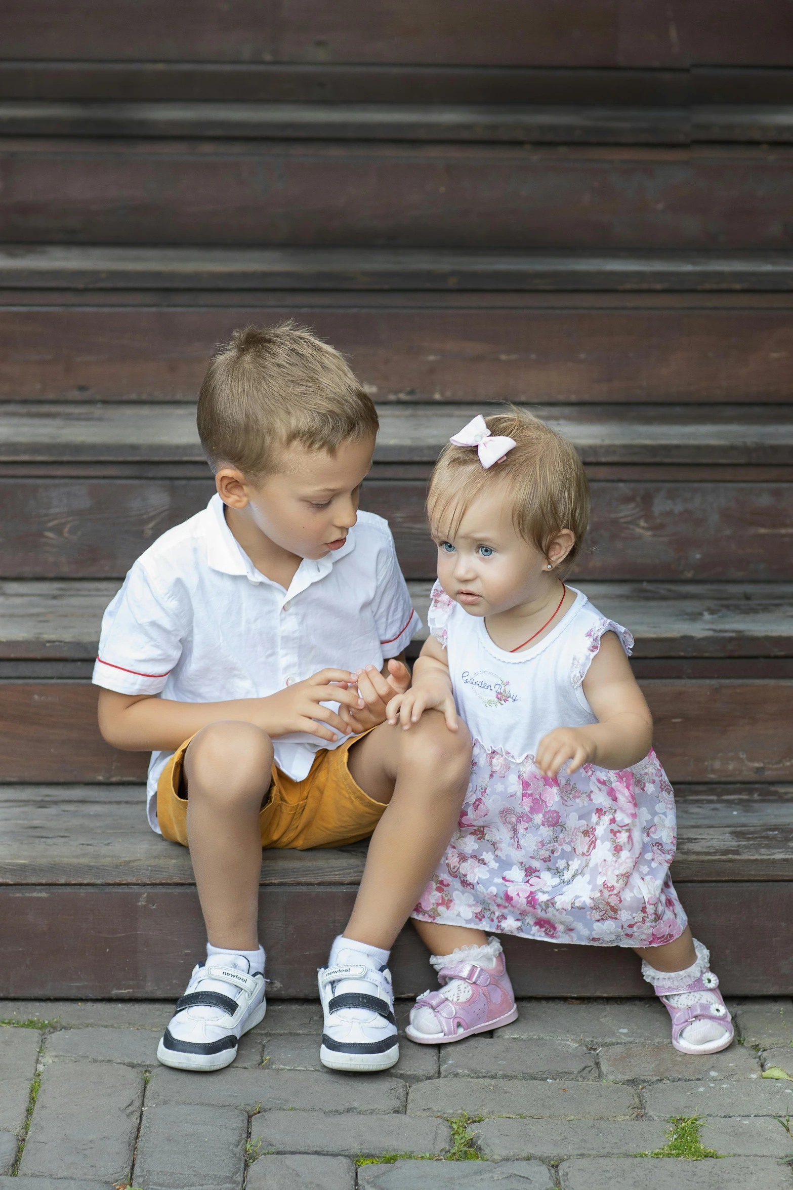 two young children sit on steps near each other