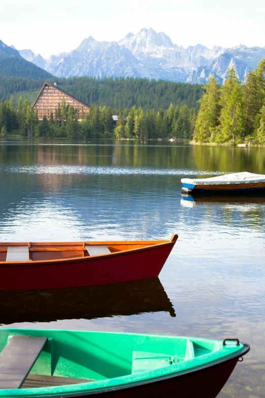 canoes sit along the shoreline of a lake near a shore house