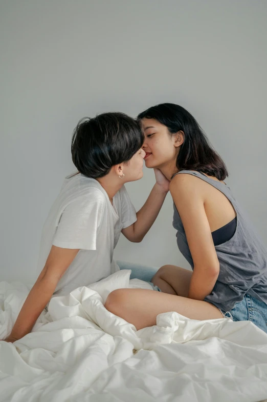 two women sharing a kiss on the bed