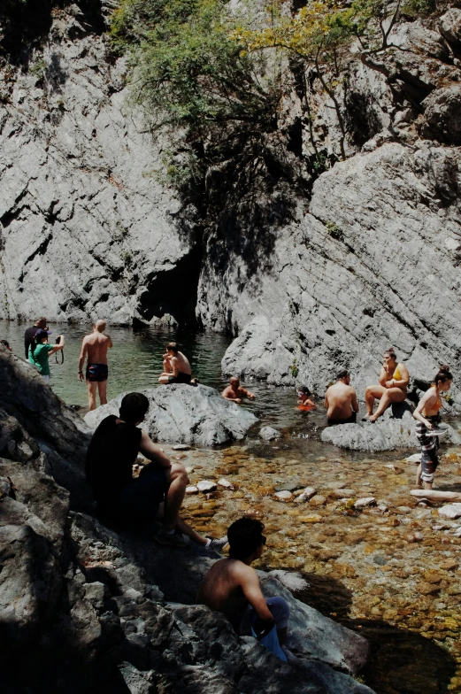 several people playing near a stream on the rock