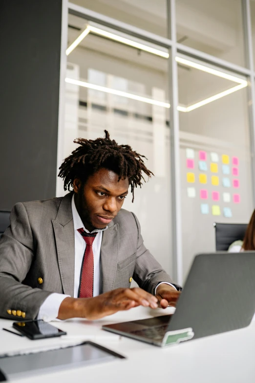 a man in business attire sitting at a table with a laptop