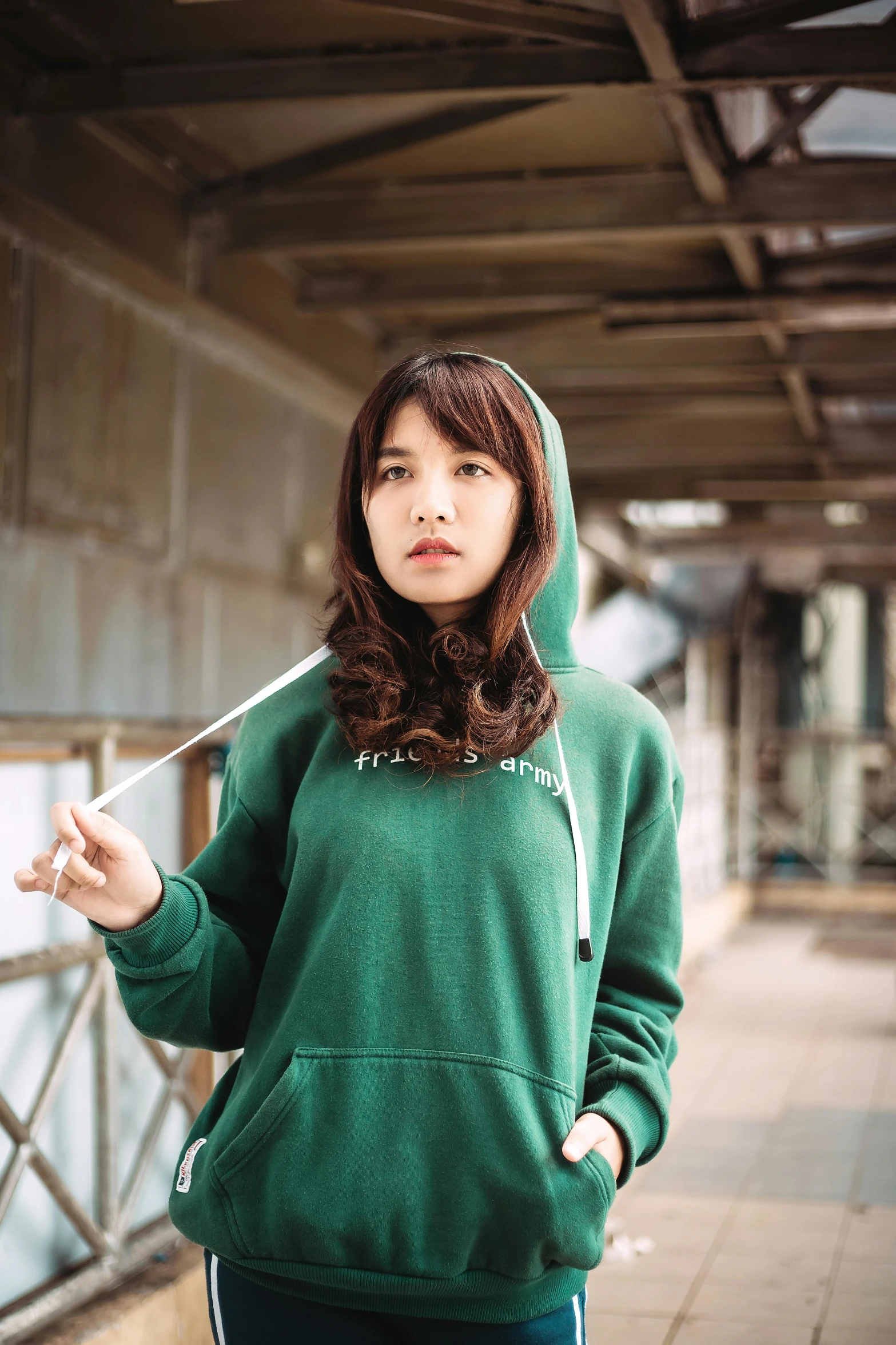 a young woman in a hooded hoodie standing in the outdoors