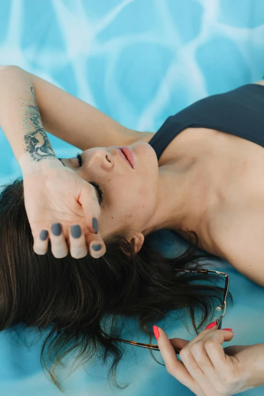 a woman laying on the edge of a pool with her hands on her head
