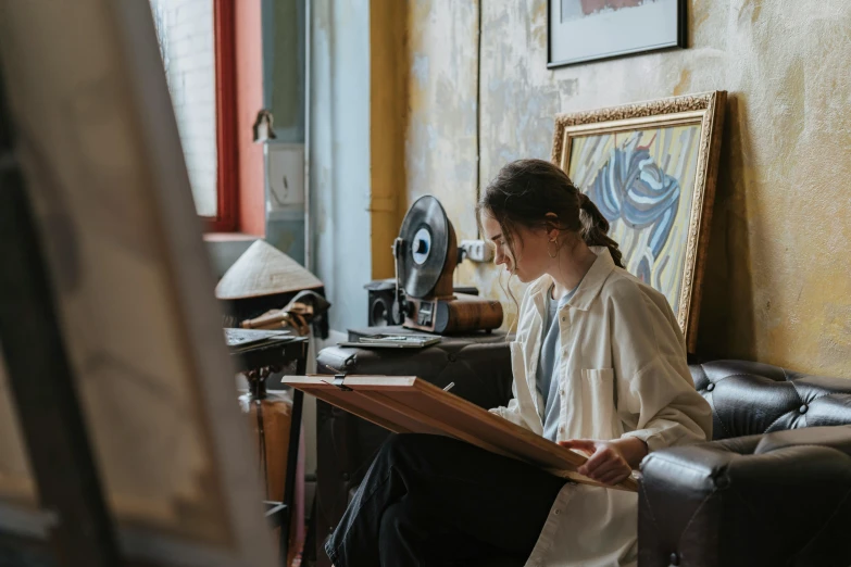 woman sitting in leather chair holding a book with art