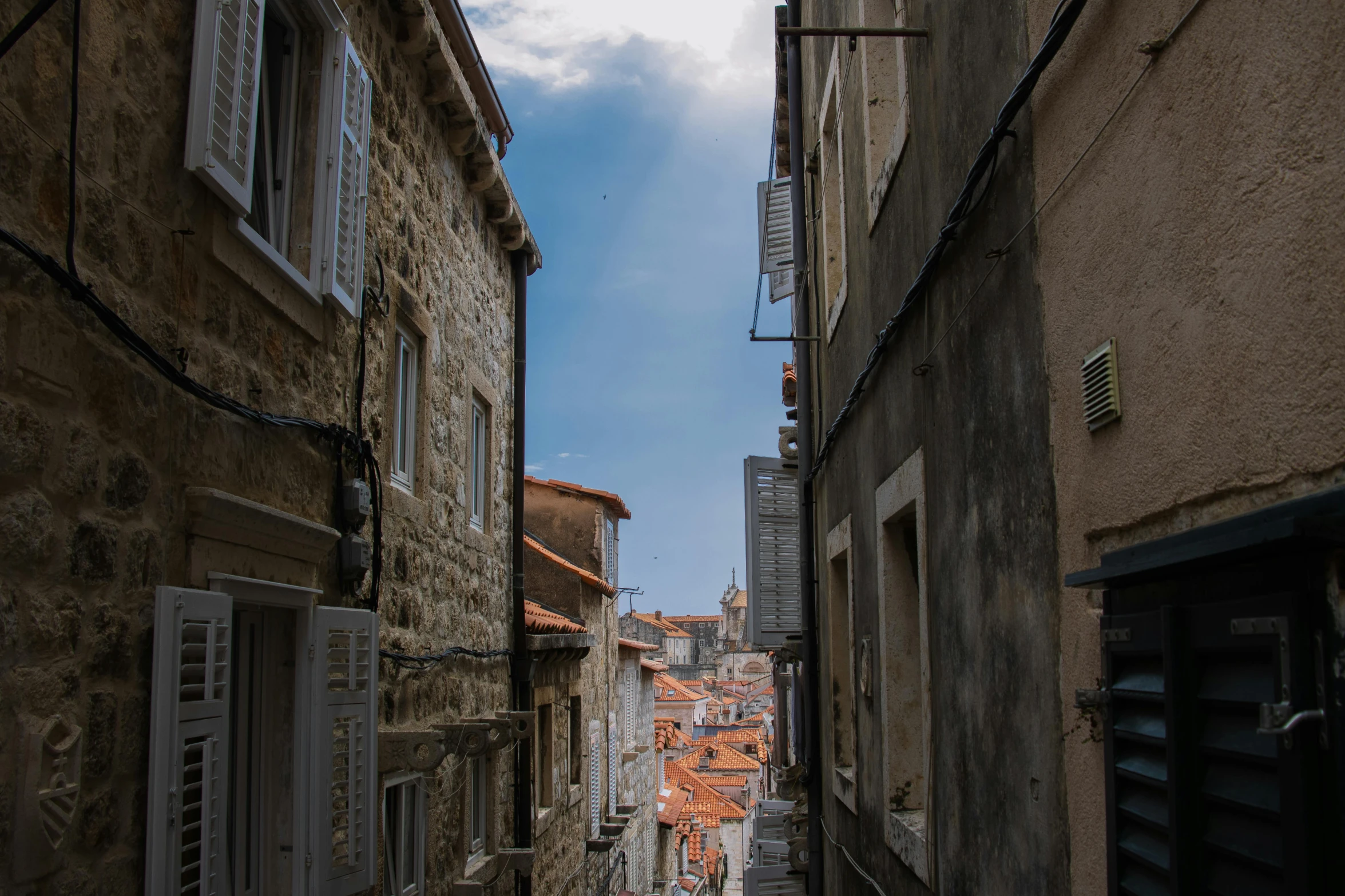 an alley with old buildings has a view of a blue sky