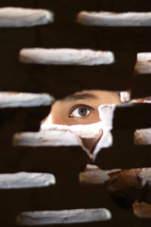 looking through the slatted wooden boards and through it is a face