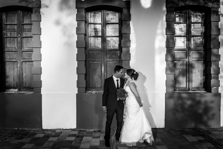 a bride and groom kissing in front of a building