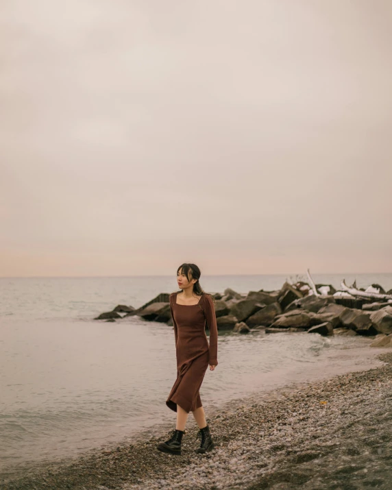 a woman in a long dress standing on the beach