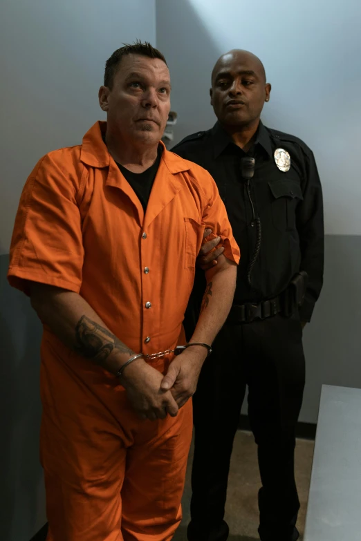 two men in orange outfits stand next to each other