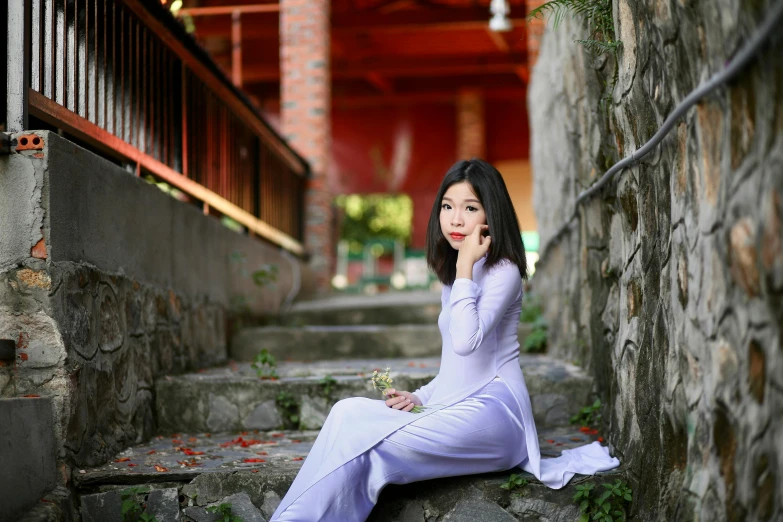 a woman with long hair sitting on steps, on her cell phone