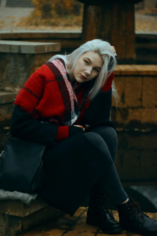 a woman with white hair and a red coat is sitting on the steps