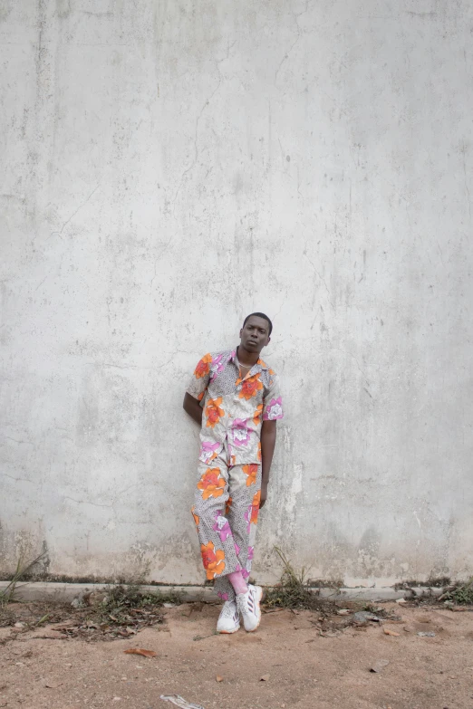 man in floral patterned pyjama leaning against the wall