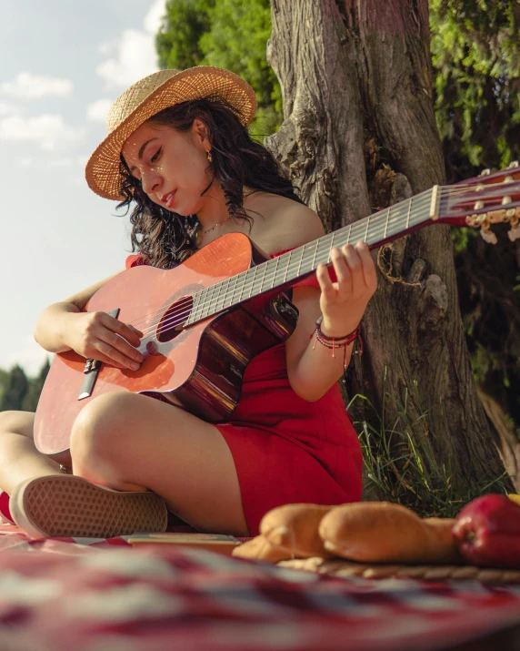 a young lady in a straw hat playing a guitar