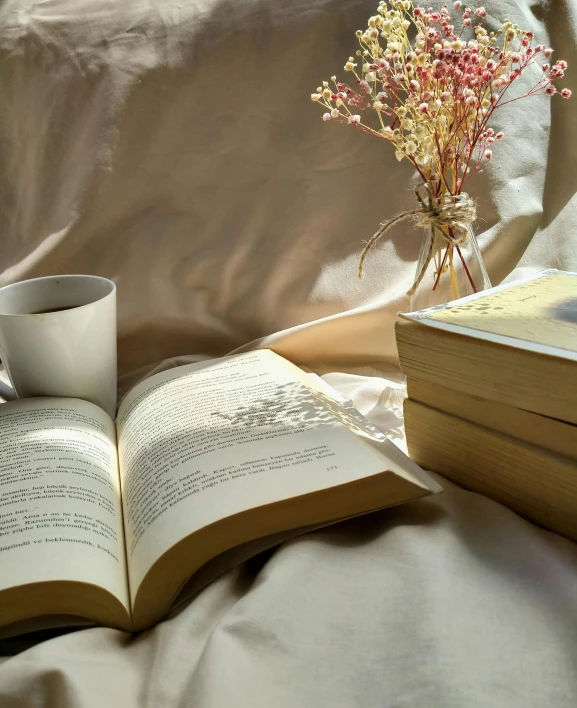 a cup of tea and some books with flowers in it