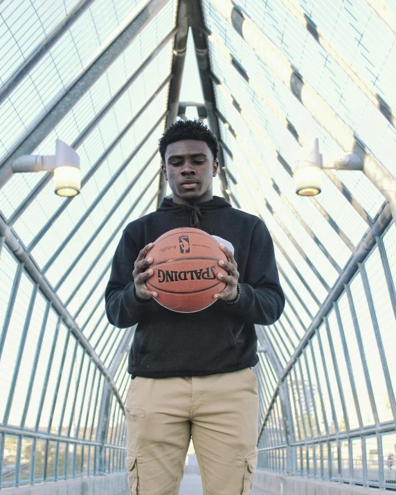 an african man holding a basketball and standing in a building