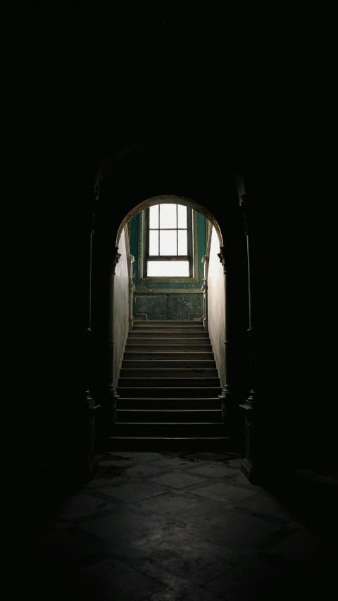 a stairway leading to a bright window in a dark room