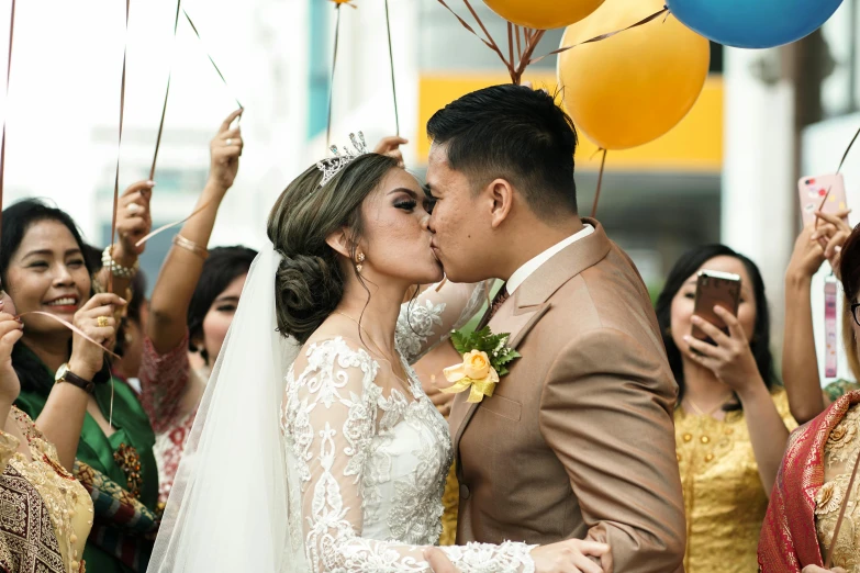 a bride and groom kissing with balloons