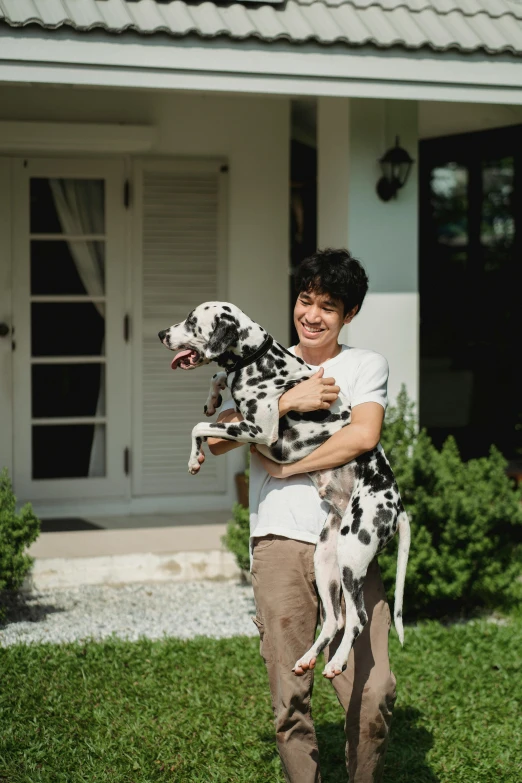 a woman is walking in the grass with two dalmatian dogs