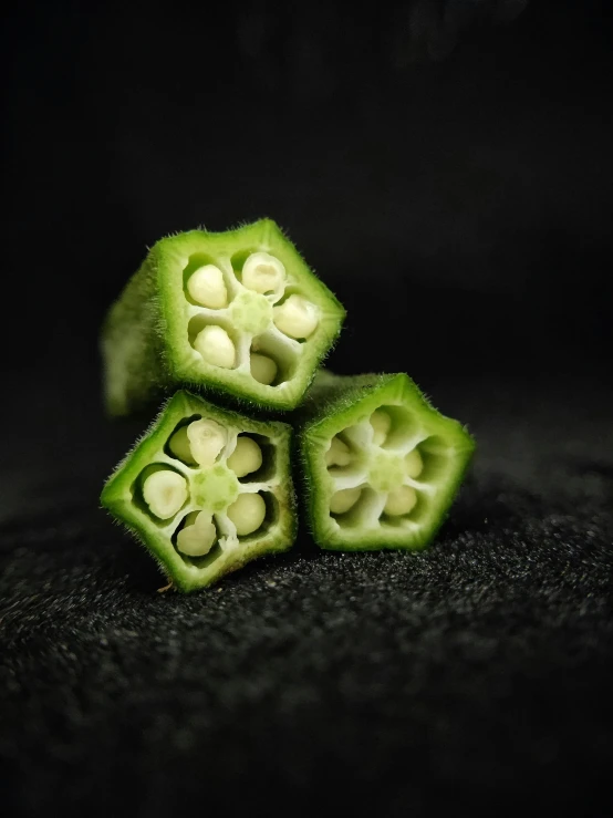 a black background with four pieces of green plant materials