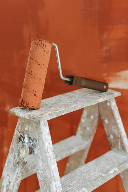 an old wooden step ladder holding a paint roller