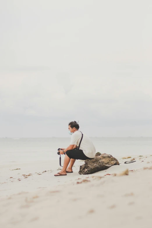 a man sits on a rock in the sand