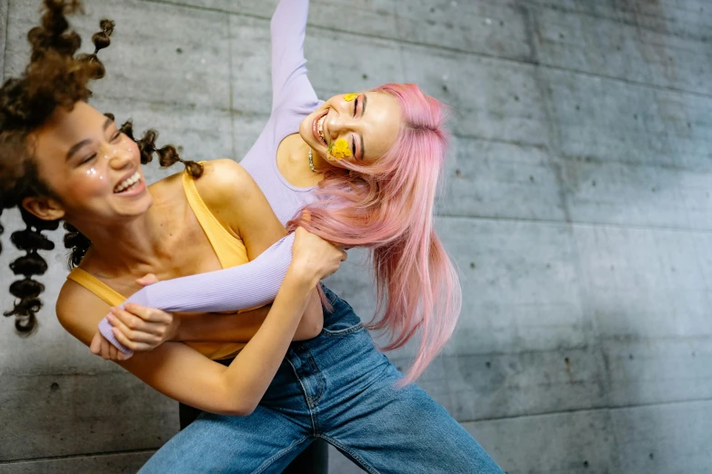 two women one in pink, one in lavender with a id and holding her hands behind her head