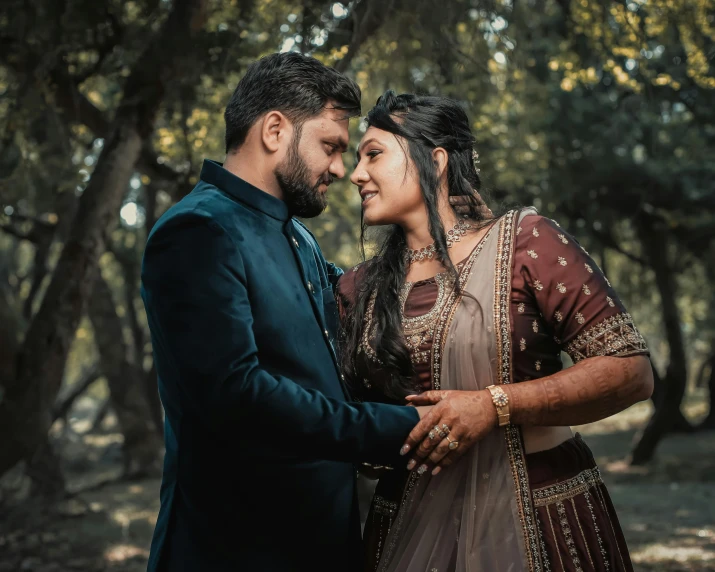 two indian women and one man emcing each other under trees