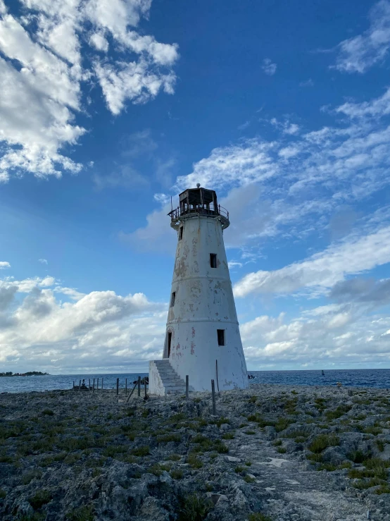 a very tall white light house next to the ocean