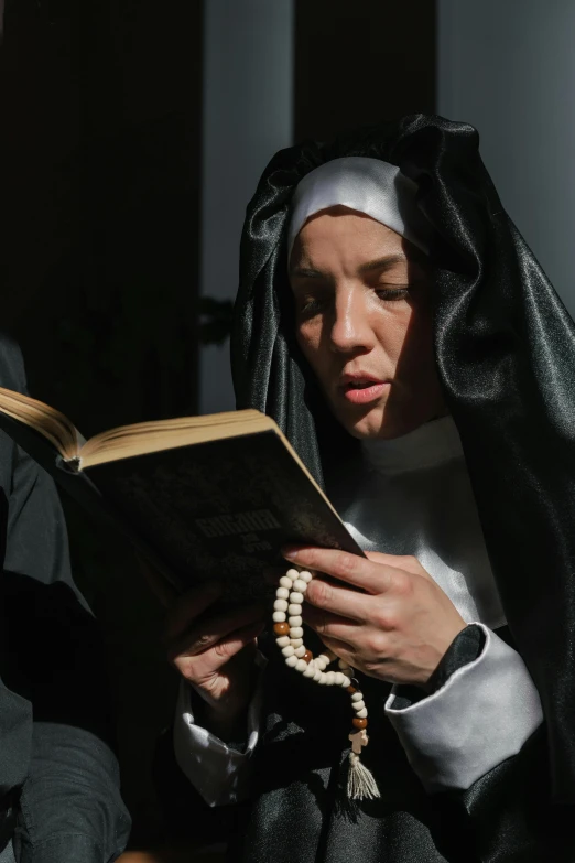 a nun reading a bible while wearing a pearl necklace