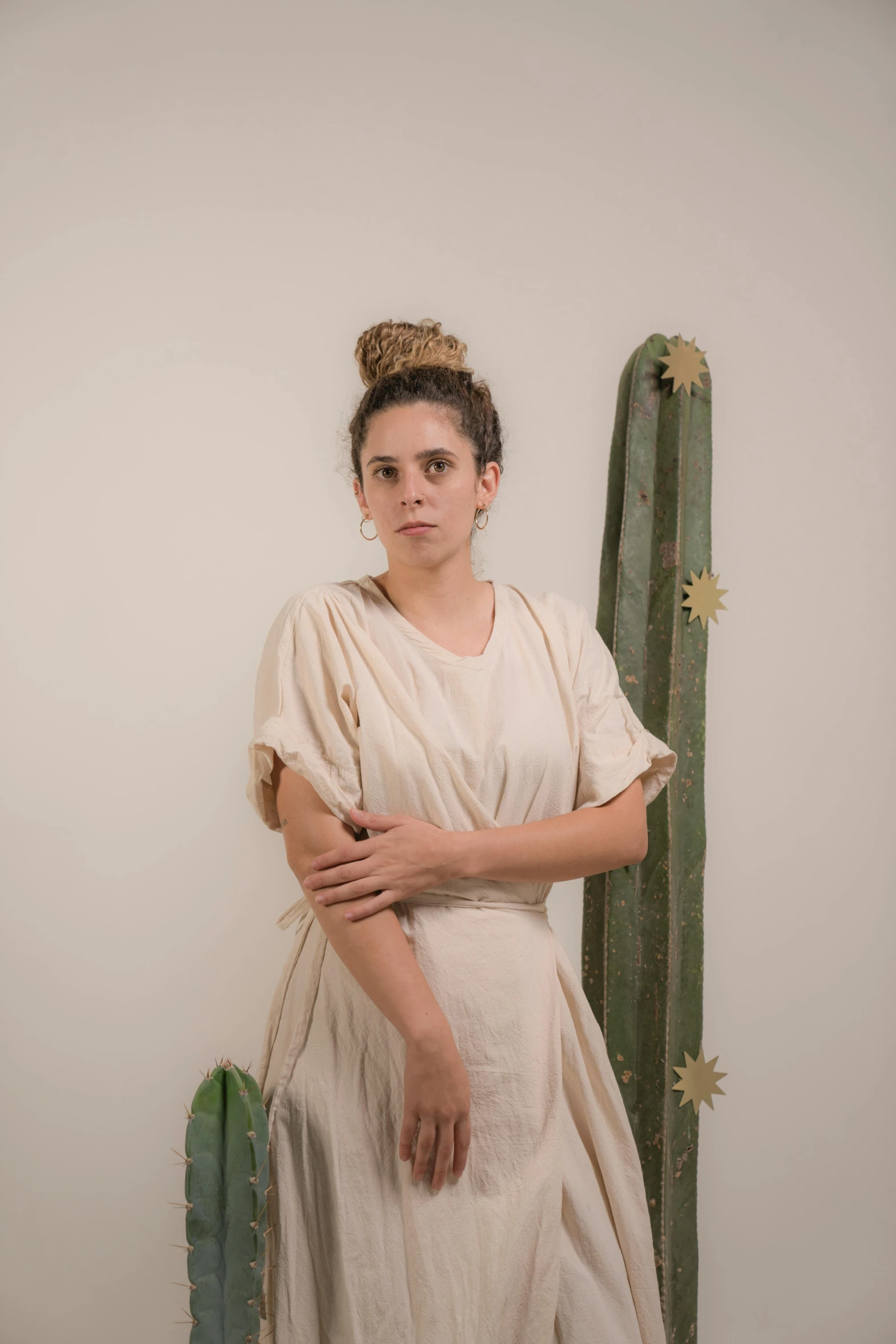 a woman is standing in front of an cactus