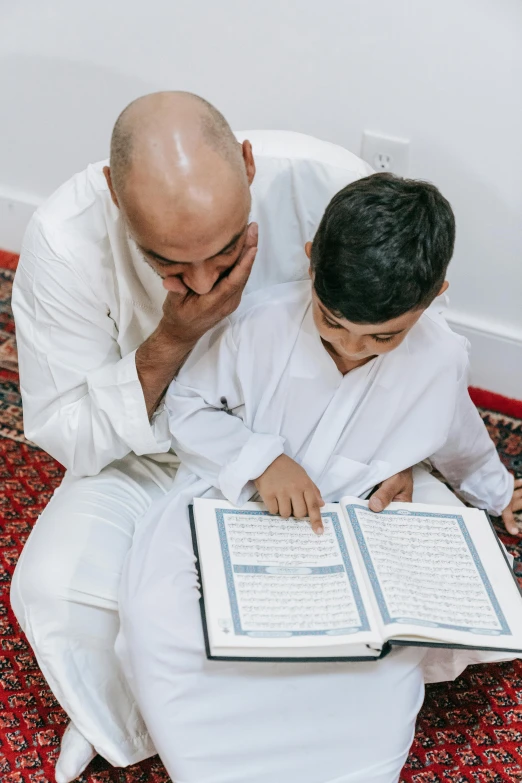 a man is reading a book as another person looks on