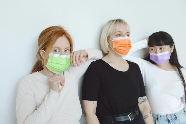 three women in black and white shirts and one is wearing orange and green face masks