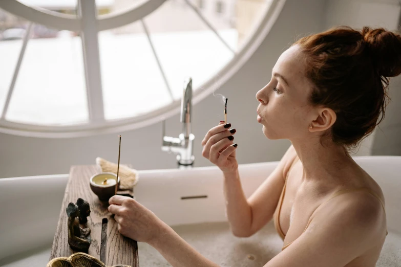 a beautiful woman sitting next to a tub holding a knife