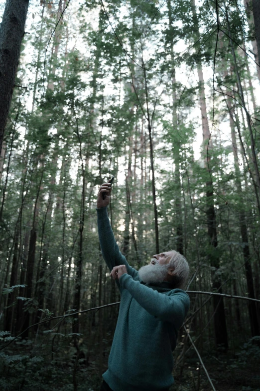 a person standing in a forest taking a po with a cellphone