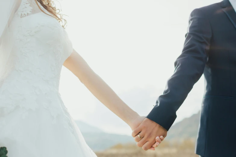 a close up of a bride and groom holding hands