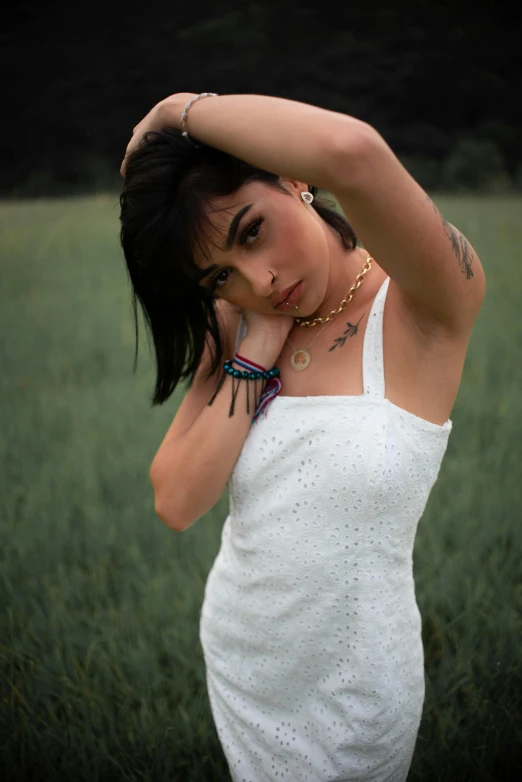 a woman in a white dress holding her hair up to her face