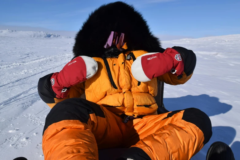 a woman sitting in the snow wearing orange pants and black hat