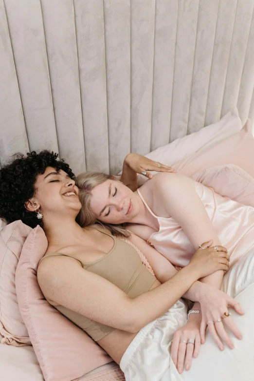 two women in underwear lying in bed together