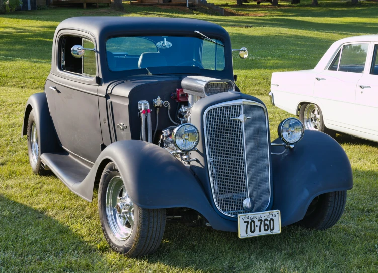 a gray and black car parked on top of a lush green field