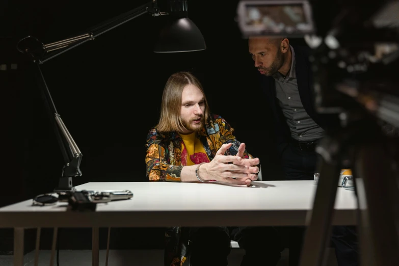 the man sitting at the desk looks at his cellphone