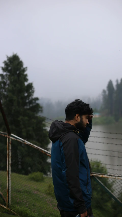 a man in a hooded jacket looks out into the distance