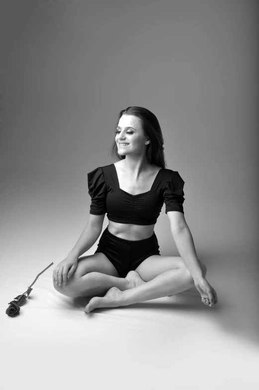 a woman sitting on the ground in a black top and white shorts