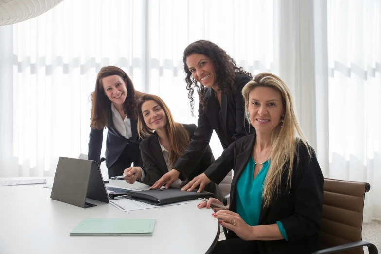 four woman sitting at a table posing for the camera