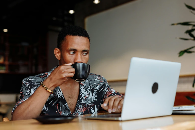 a man sitting at a table with a coffee cup next to a laptop computer