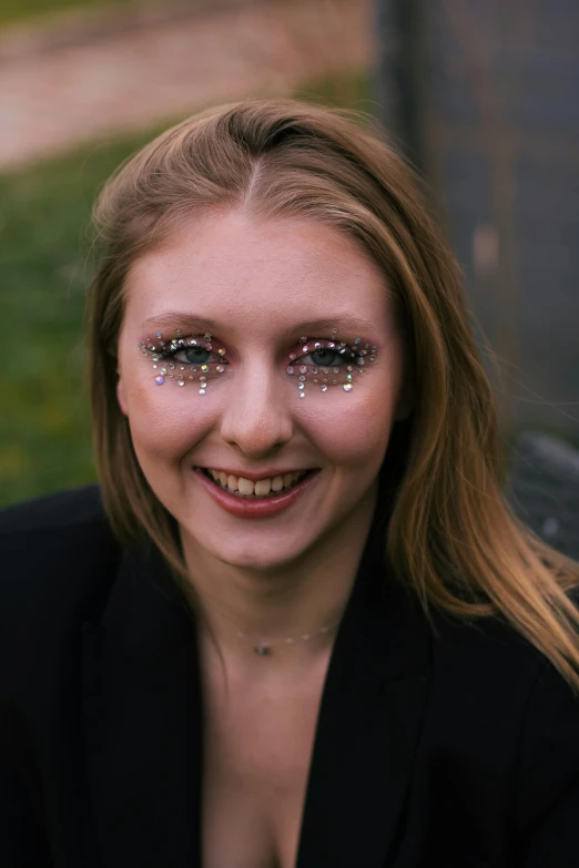 a smiling young woman wearing bright pink glitter makeup