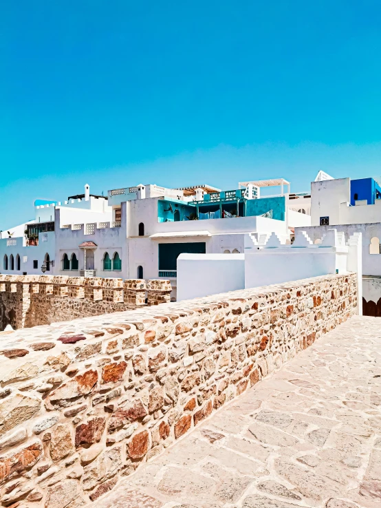 a stone wall near the water with white buildings