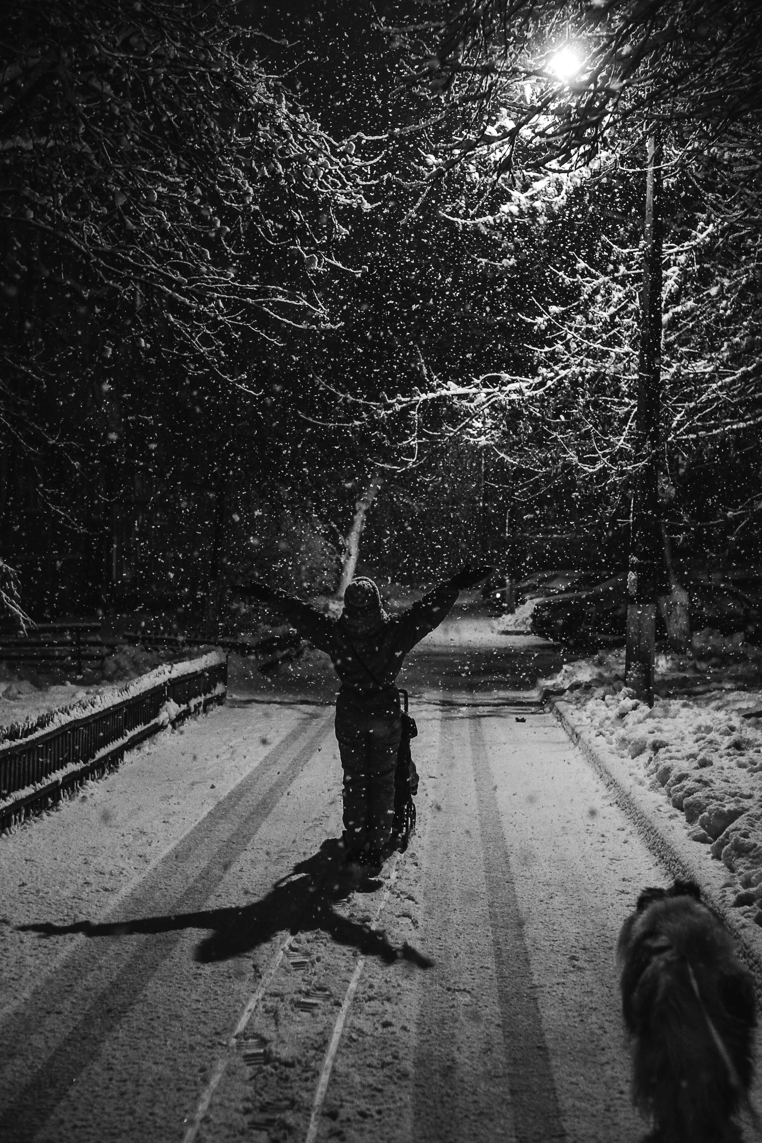 a man with his arms wide open walking across a snow covered road