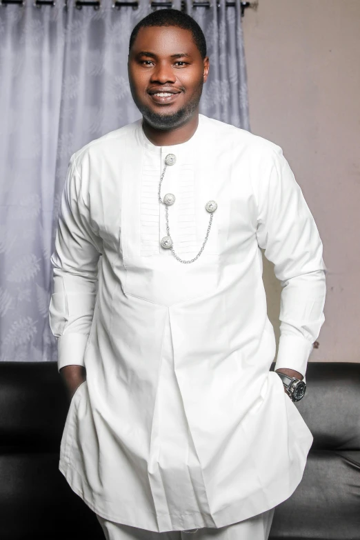 a black man in white suit smiling and standing